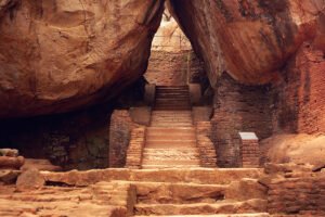 Stone stairway under massive rock at Sigiriya fortress, ancient brick walls visible