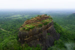 Aerial view of Sigiriya rock fortress perched above lush green Sri Lankan forest