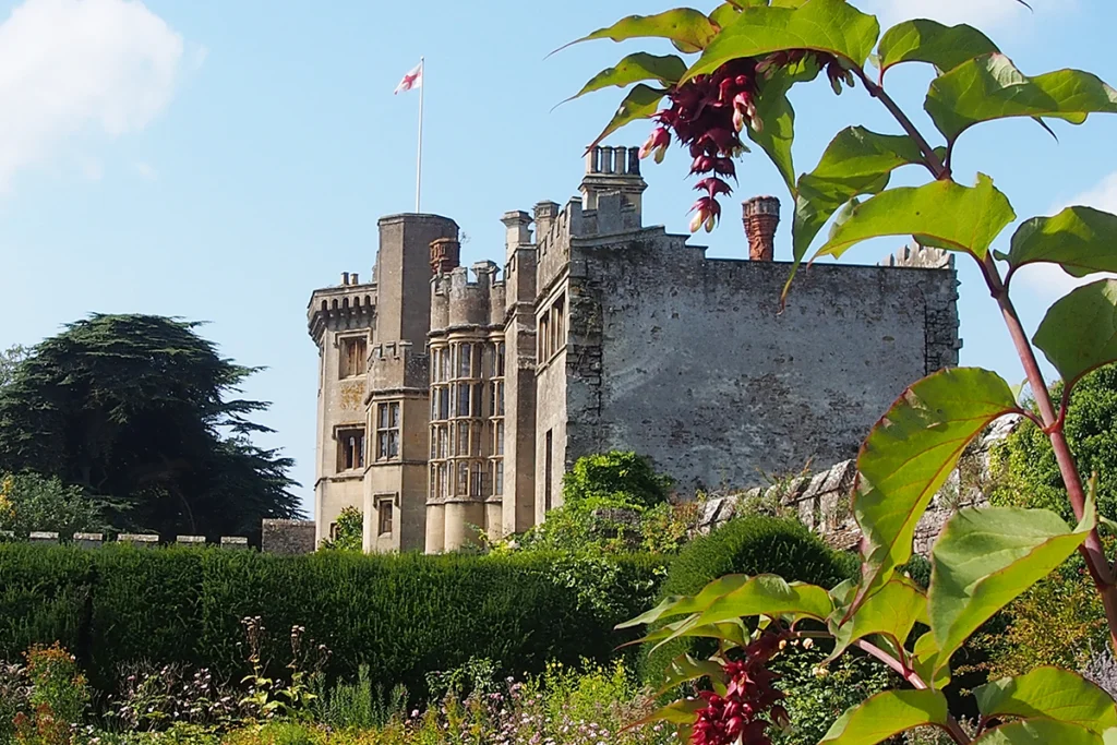 Stone facade and gardens of Thornbury Castle under blue sky