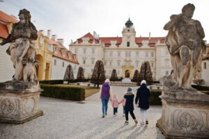 Visitors approaching Valtice Castle courtyard between statues