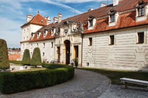 Valtice Castle exterior with ornate entrance, trimmed gardens and red-tiled roof