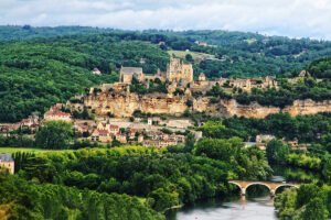 View of Château de Beynac atop limestone cliff above Dordogne River and village