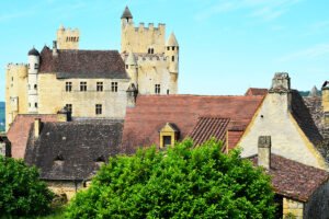 Stone Château de Beynac above terracotta village roofs