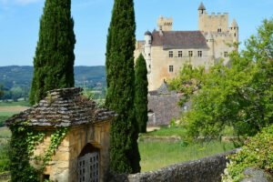 Château de Beynac seen from garden path with cypress trees and stone archway