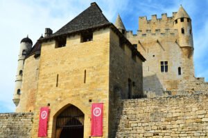 Stone façade of Château de Beynac with towers and blue sky