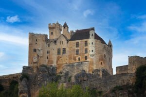 Château de Beynac perched on limestone cliff under blue sky