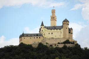 Marksburg Castle on rocky hill above forest and Rhine