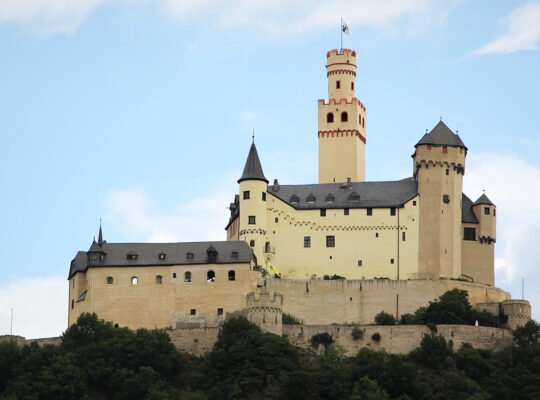 Marksburg Castle perched on hill with blue sky backdrop