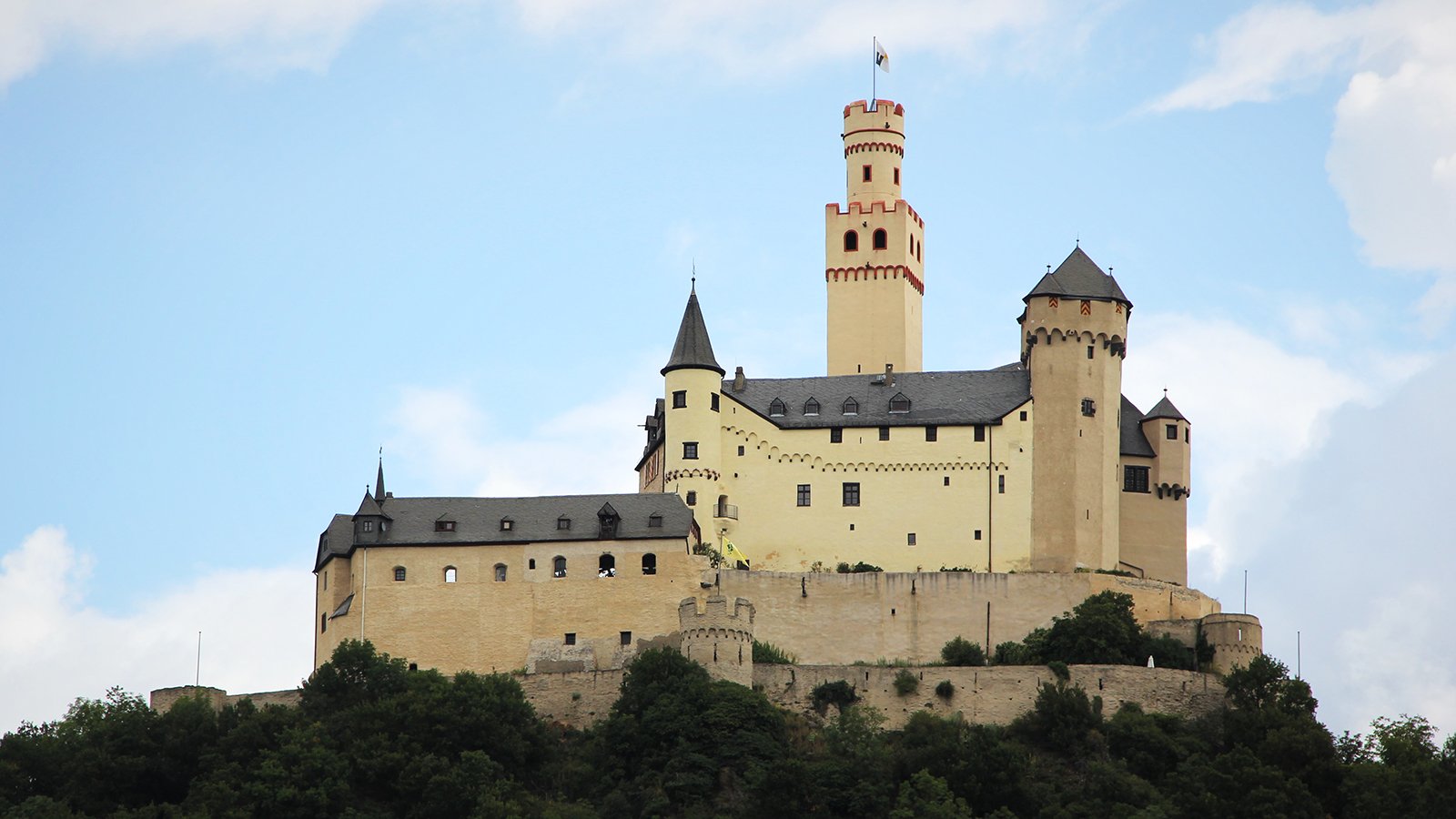 Marksburg Castle perched on hill with blue sky backdrop