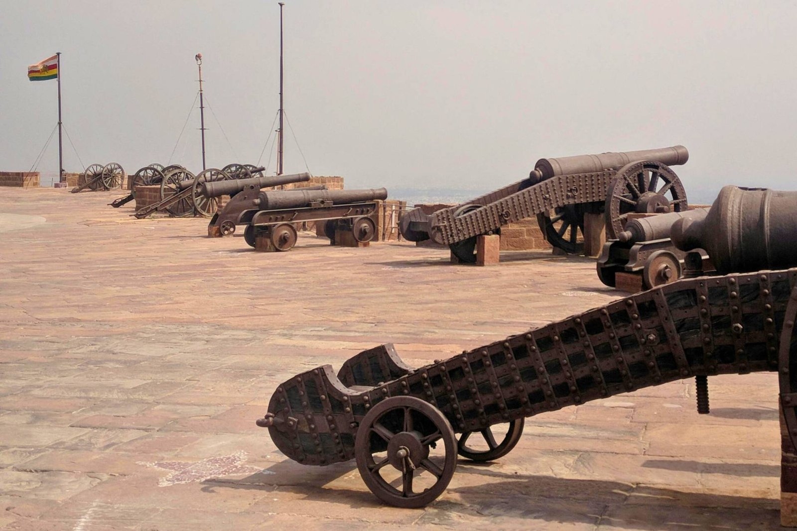 Row of historic cannons on the ramparts of Mehrangarh Fort in Jodhpur, India, overlooking the surrounding landscape.